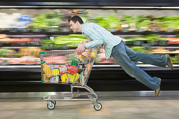 Man leaning on moving shopping cart with blurred background